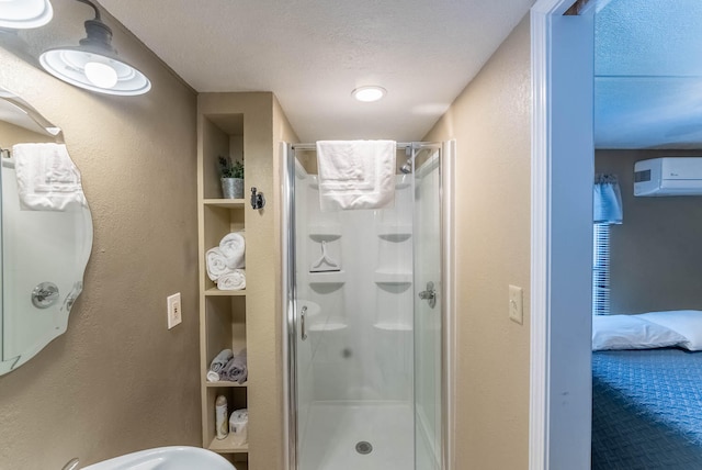 bathroom featuring an AC wall unit, a shower with door, and a textured ceiling