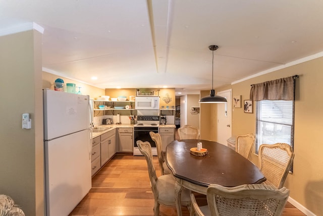 dining area featuring ornamental molding, sink, and light hardwood / wood-style flooring