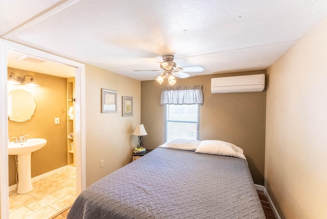 bedroom with ensuite bathroom, ceiling fan, sink, a wall mounted air conditioner, and a textured ceiling