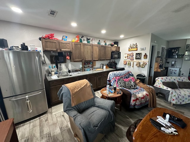 kitchen featuring black appliances, light hardwood / wood-style flooring, dark brown cabinetry, and sink