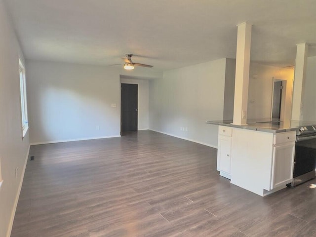 unfurnished living room featuring ceiling fan and dark wood-type flooring