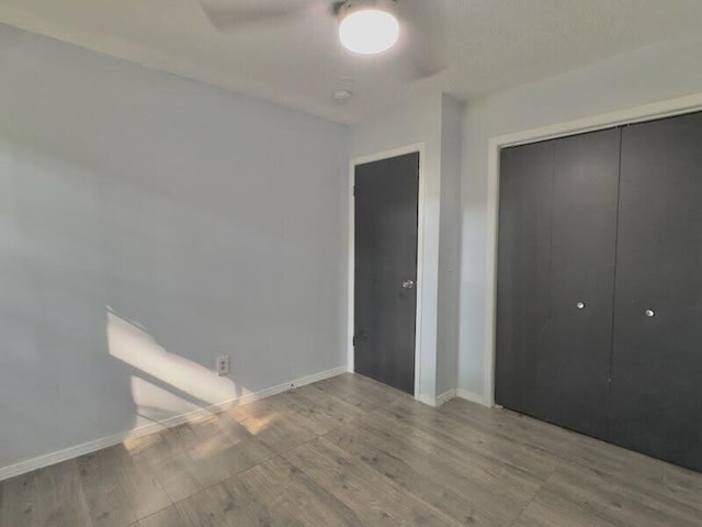 unfurnished bedroom featuring light wood-type flooring, ceiling fan, and a closet