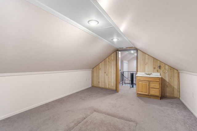 bonus room featuring lofted ceiling, light colored carpet, sink, and wooden walls