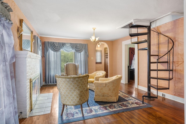 sitting room featuring a brick fireplace, hardwood / wood-style floors, and a notable chandelier