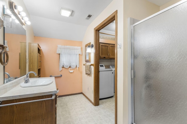 bathroom featuring an enclosed shower, washer and clothes dryer, and vanity