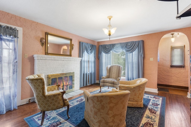 sitting room with a brick fireplace and dark wood-type flooring