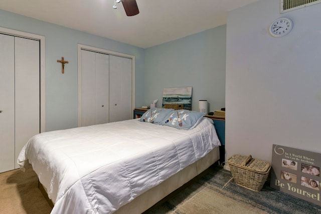 bedroom featuring dark colored carpet, two closets, and ceiling fan