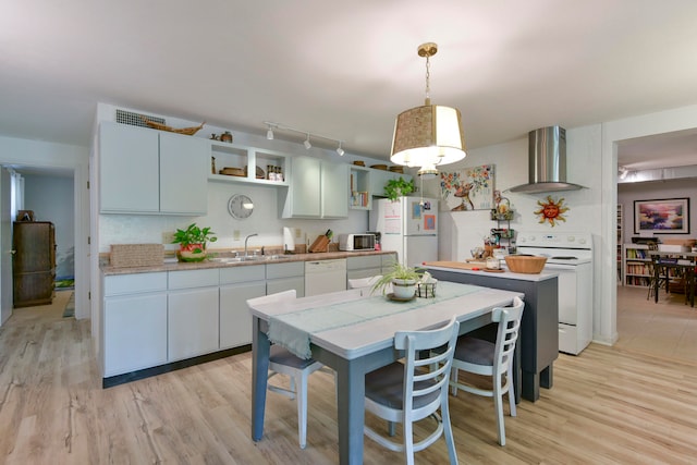 kitchen with wall chimney range hood, sink, pendant lighting, light wood-type flooring, and white appliances