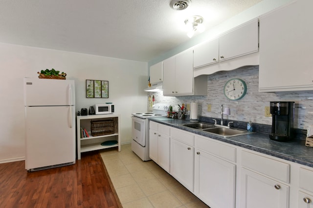 kitchen with wood-type flooring, backsplash, sink, white cabinets, and white appliances