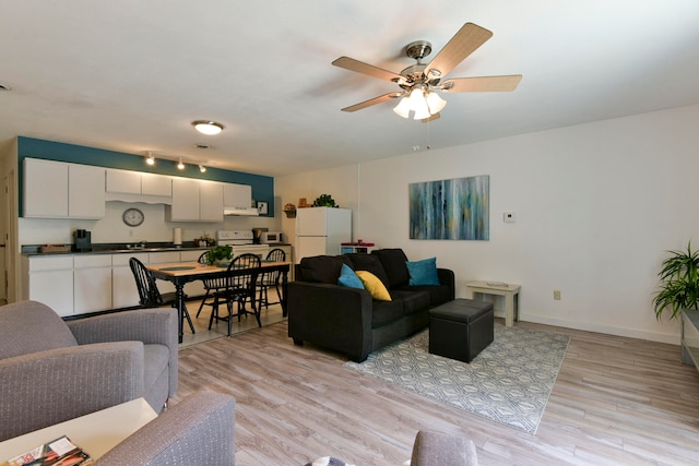 living room with sink, light wood-type flooring, and ceiling fan