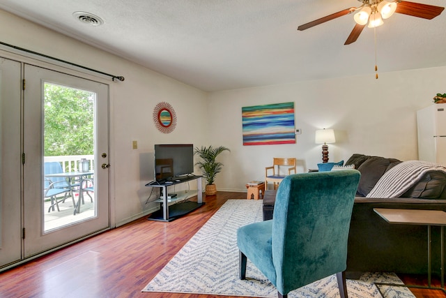 living room featuring ceiling fan, a textured ceiling, and hardwood / wood-style floors