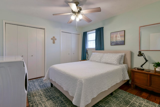 bedroom featuring ceiling fan, washer / clothes dryer, dark hardwood / wood-style flooring, and two closets