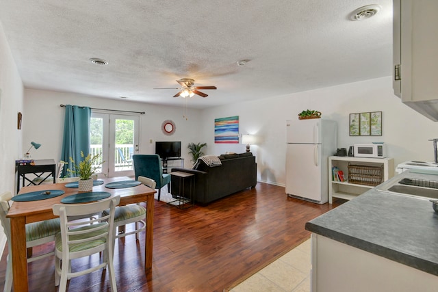 interior space featuring french doors, ceiling fan, wood-type flooring, and a textured ceiling