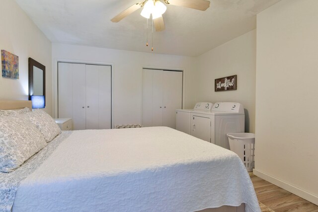 bedroom featuring light hardwood / wood-style flooring, washer and dryer, two closets, and ceiling fan