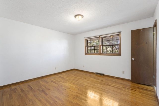 spare room featuring a textured ceiling and light hardwood / wood-style flooring