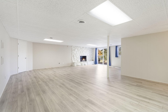 unfurnished living room featuring a fireplace, light wood-type flooring, and a paneled ceiling