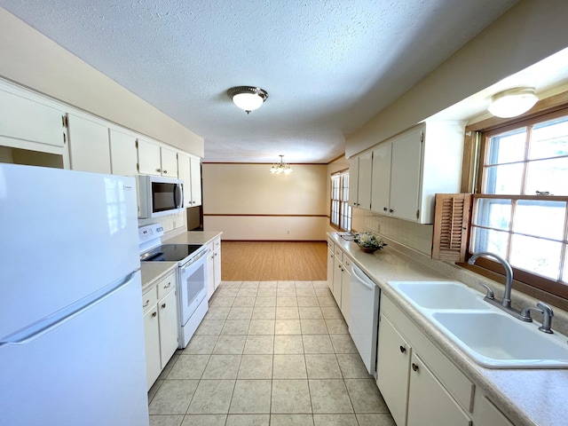 kitchen featuring white cabinetry, sink, white appliances, and a notable chandelier