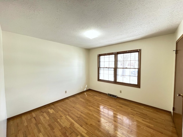 unfurnished room featuring a textured ceiling and hardwood / wood-style flooring