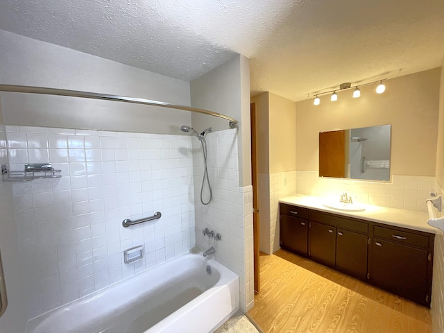 bathroom with hardwood / wood-style flooring, tiled shower / bath combo, a textured ceiling, and vanity