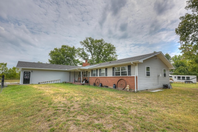 single story home featuring a chimney, brick siding, and a front yard