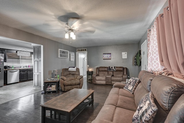 living room featuring ceiling fan, a textured ceiling, and dark wood-type flooring