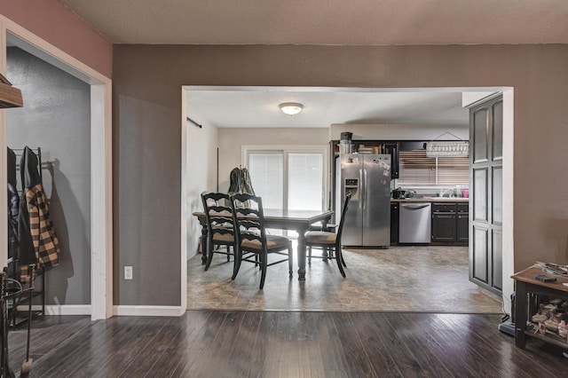 dining area with dark wood-type flooring and a textured ceiling