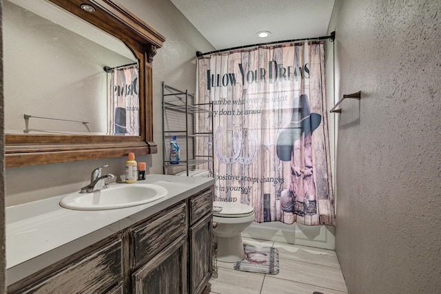 full bath with a textured wall, shower / tub combo, toilet, and vanity