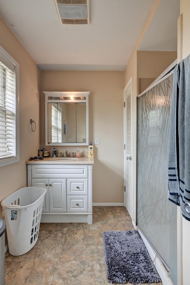 bathroom featuring a freestanding bath, baseboards, stone finish flooring, a shower stall, and vanity