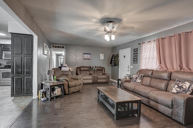 living room featuring ceiling fan, dark wood-type flooring, and a textured ceiling