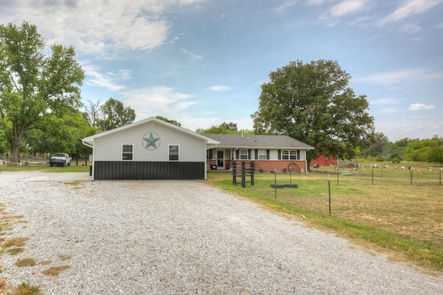 single story home featuring brick siding, driveway, fence, and a front yard