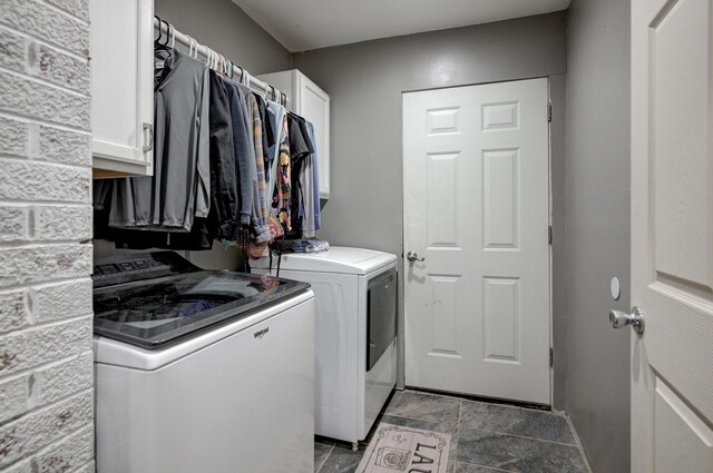 laundry room featuring washer and dryer, cabinet space, and stone finish floor