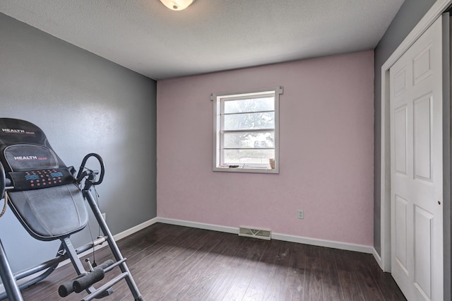exercise room featuring a textured ceiling, wood finished floors, and visible vents