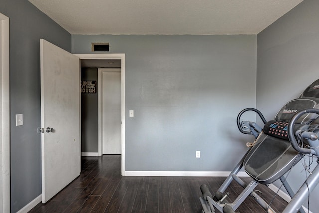 exercise room with a textured ceiling and dark hardwood / wood-style flooring