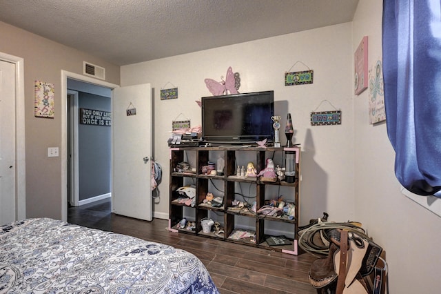 bedroom featuring a textured ceiling and dark hardwood / wood-style flooring