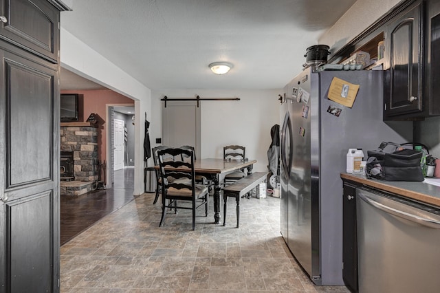 dining area featuring a stone fireplace, hardwood / wood-style floors, and a barn door