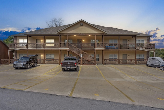 property at dusk with stairway and uncovered parking