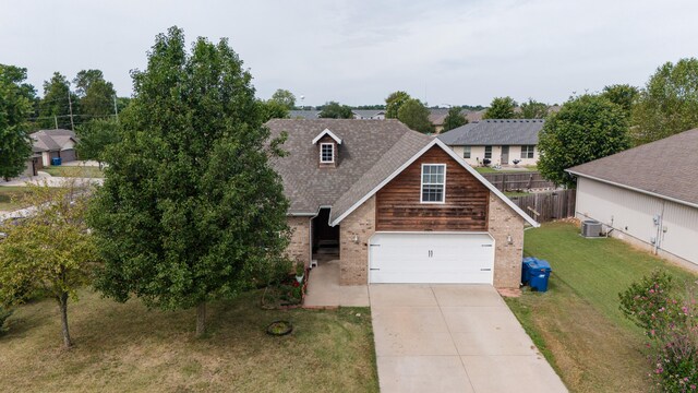 view of front facade with central AC unit, a garage, and a front yard