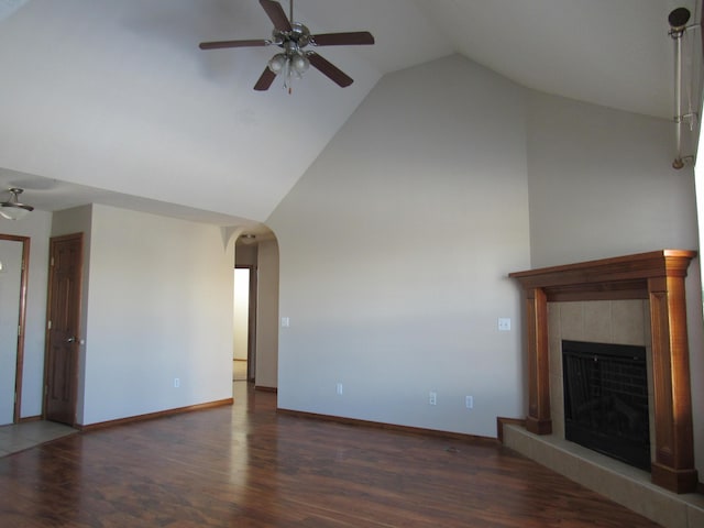 unfurnished living room with dark hardwood / wood-style floors, ceiling fan, a tile fireplace, and vaulted ceiling