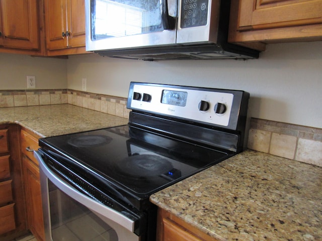 kitchen featuring black range with electric stovetop and light stone counters