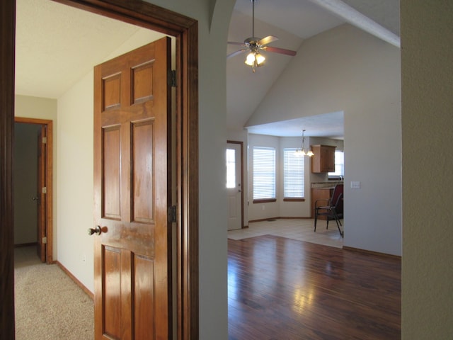 hall with hardwood / wood-style floors, lofted ceiling, and an inviting chandelier