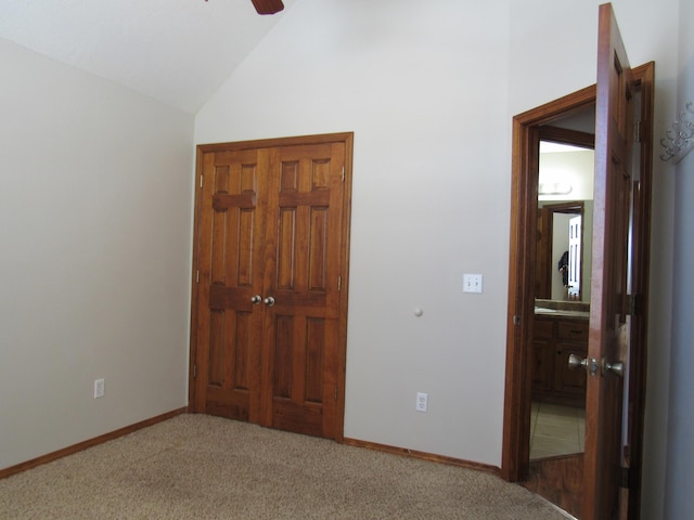 unfurnished bedroom featuring carpet flooring, ensuite bathroom, vaulted ceiling, and ceiling fan