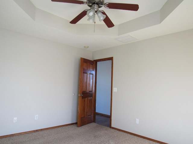 unfurnished room featuring light carpet, a raised ceiling, and ceiling fan