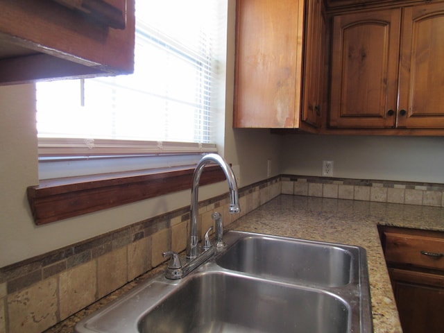 kitchen featuring light stone counters and sink