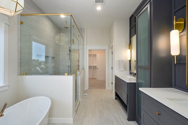3940 E Ridgeview St, Springfield, MO 65809 - bathroom featuring a shower stall, two vanities, a freestanding tub, wood finished floors, and recessed lighting