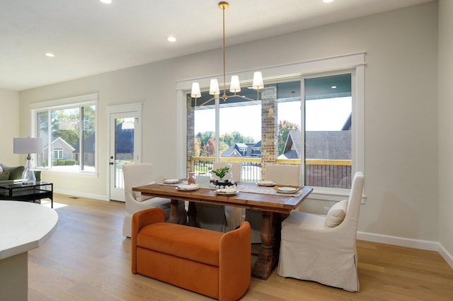 dining space with a notable chandelier and light hardwood / wood-style flooring