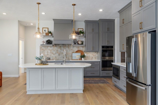 kitchen featuring gray cabinets, appliances with stainless steel finishes, pendant lighting, and light wood-type flooring