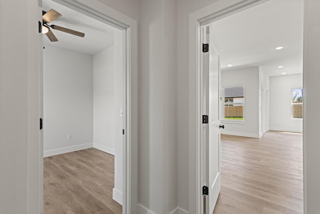 corridor with light wood finished floors, baseboards, and recessed lighting
