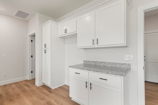 kitchen featuring light stone counters, light hardwood / wood-style flooring, and white cabinetry