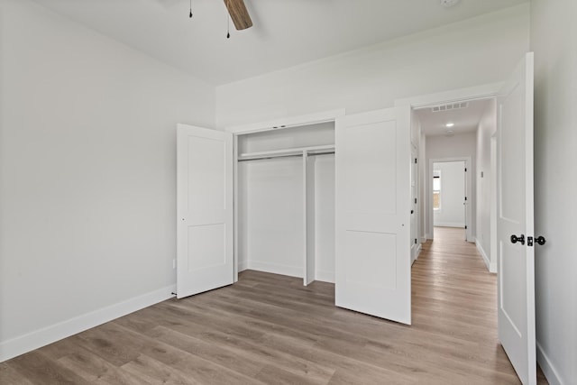 unfurnished bedroom with baseboards, light wood-style floors, visible vents, and a closet