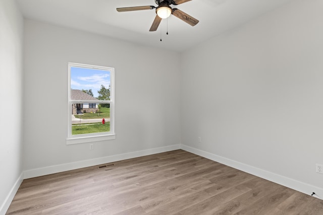 empty room featuring light wood-style floors, visible vents, baseboards, and ceiling fan